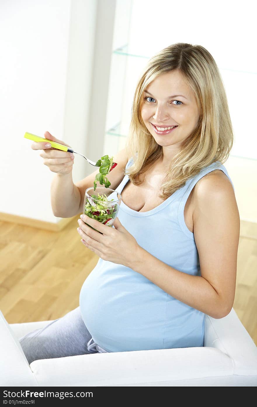 Young pregnant woman eating salad out of a glas. Young pregnant woman eating salad out of a glas