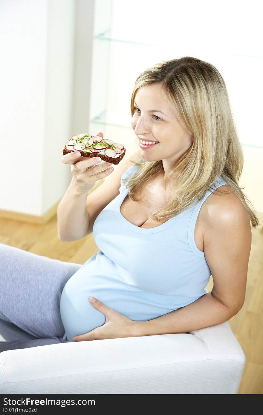 Pregnant woman eats wholemeal bread with radishes