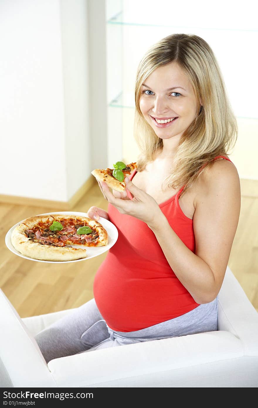 Young pregnant woman eating pizza