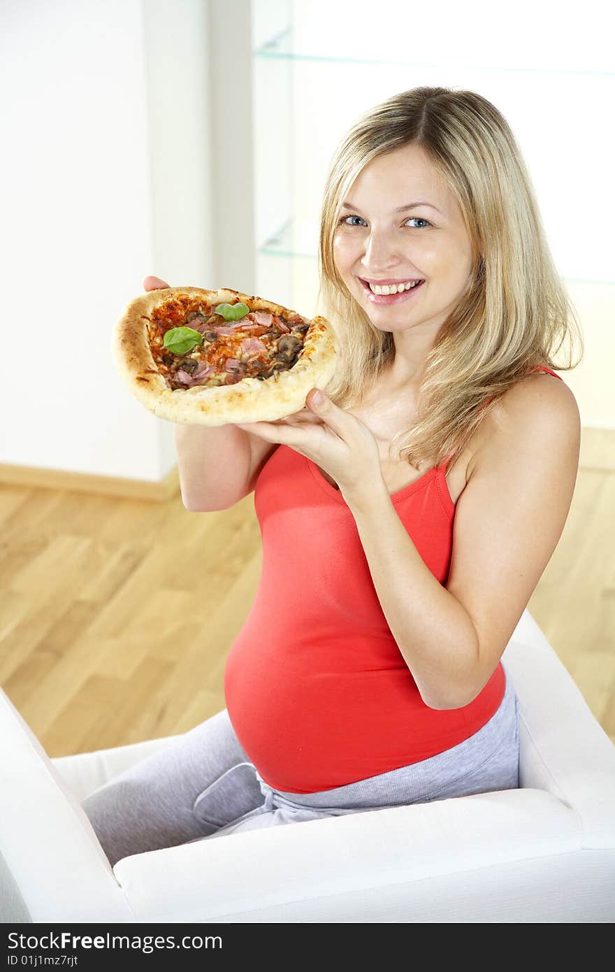 Young pregnant woman eating pizza