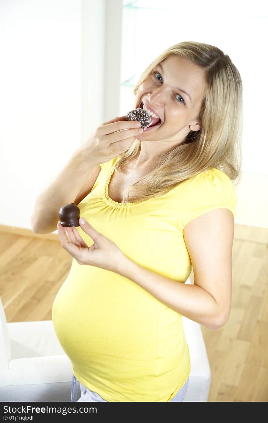 Young, beautiful pregnant woman is eating chocolate bombs. Young, beautiful pregnant woman is eating chocolate bombs