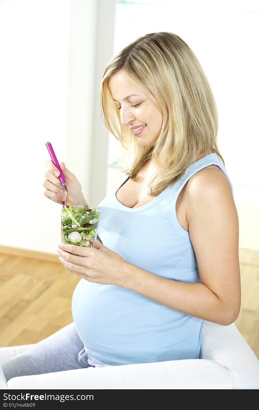 Pregnant woman is eating salad