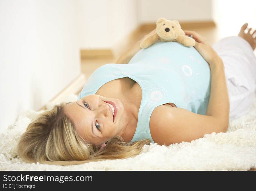 Pregnant woman keeps teddy on her belly. Pregnant woman keeps teddy on her belly