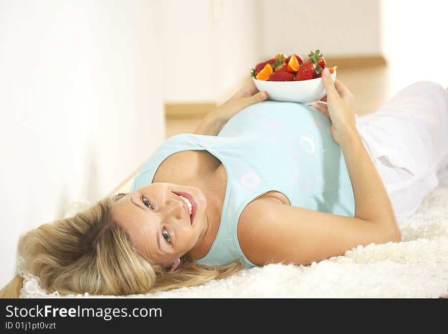 Young pretty pregnant woman eats strawberries