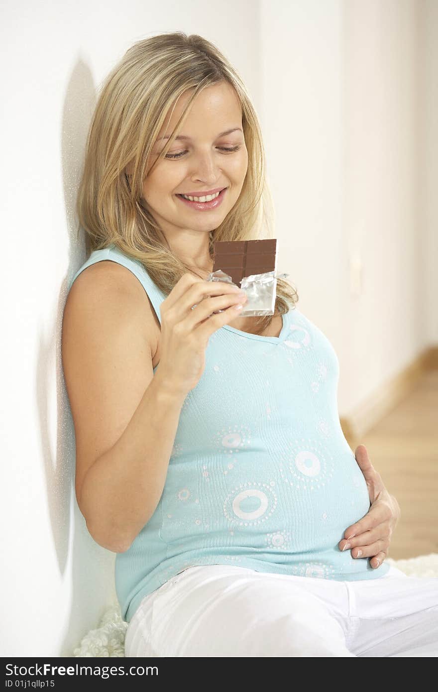 Young beautiful pregnant woman eats chocolate. Young beautiful pregnant woman eats chocolate