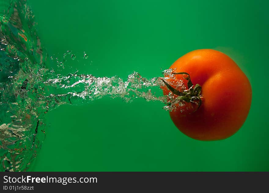 Tomato in water on a green background