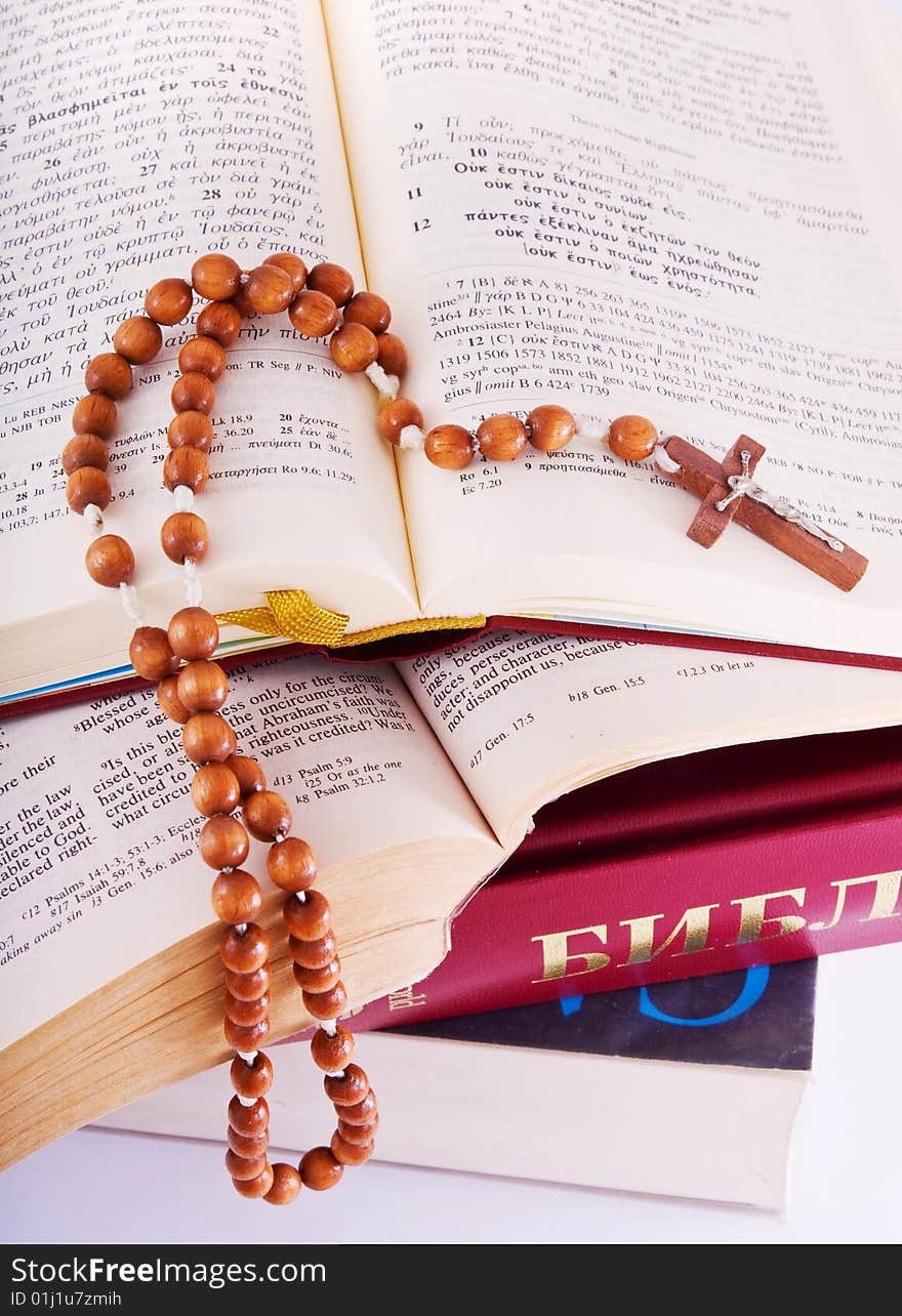 Open Holy Bible lying on stack of old books with glasses, cross and beads. Open Holy Bible lying on stack of old books with glasses, cross and beads