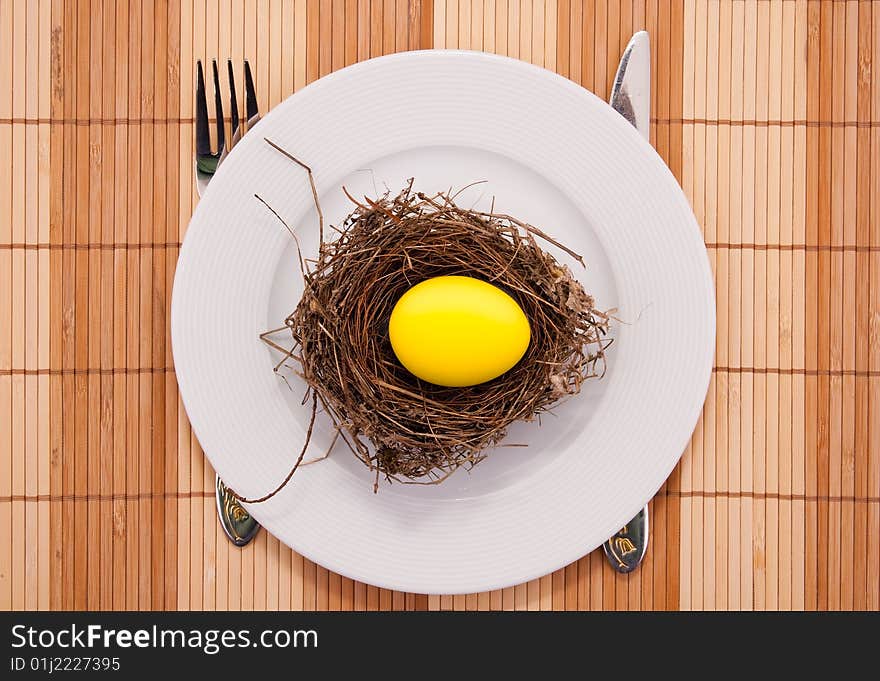 Golden egg in a nest served on a plate