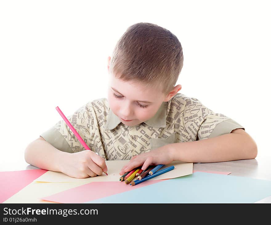 6 year old boy draws pencils sitting for a table. 6 year old boy draws pencils sitting for a table