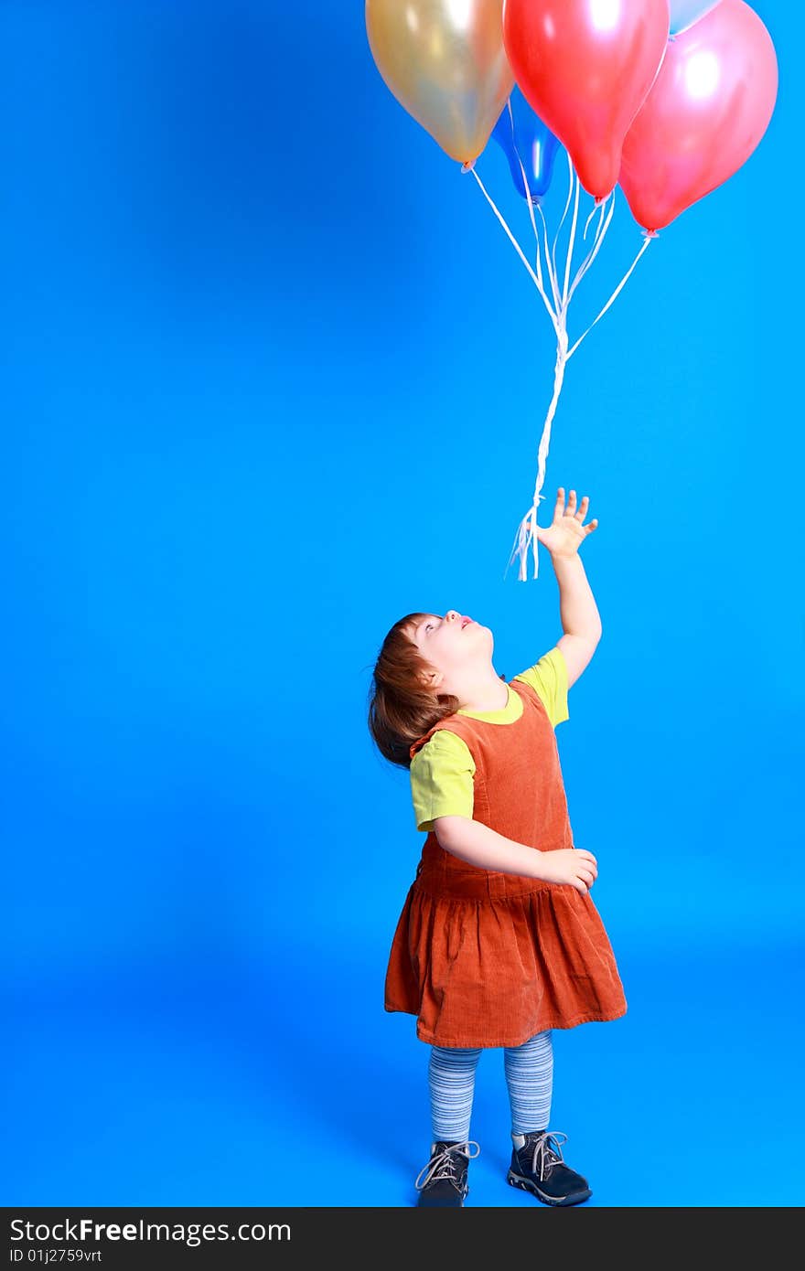 Little girl holding colorful balloons on a blue background. Little girl holding colorful balloons on a blue background