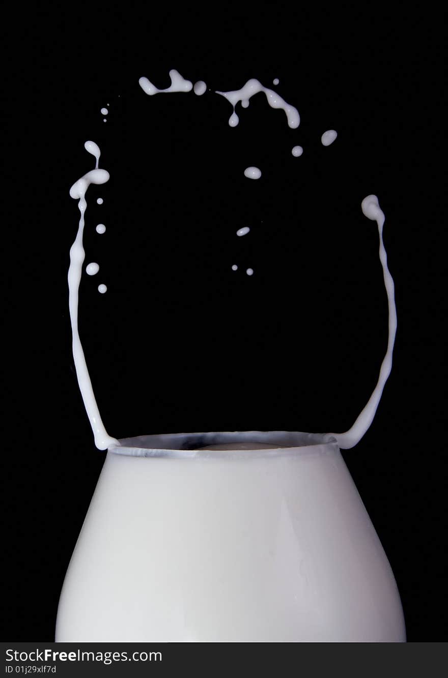 Splash milk in the glass on the black background