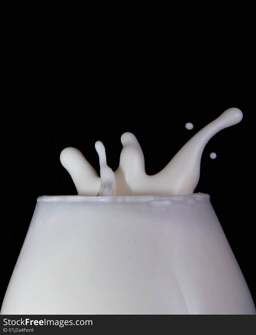 Splash milk in the glass on the black background