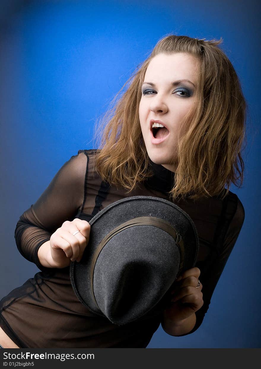 Emotional girl dancing with hat on blue background