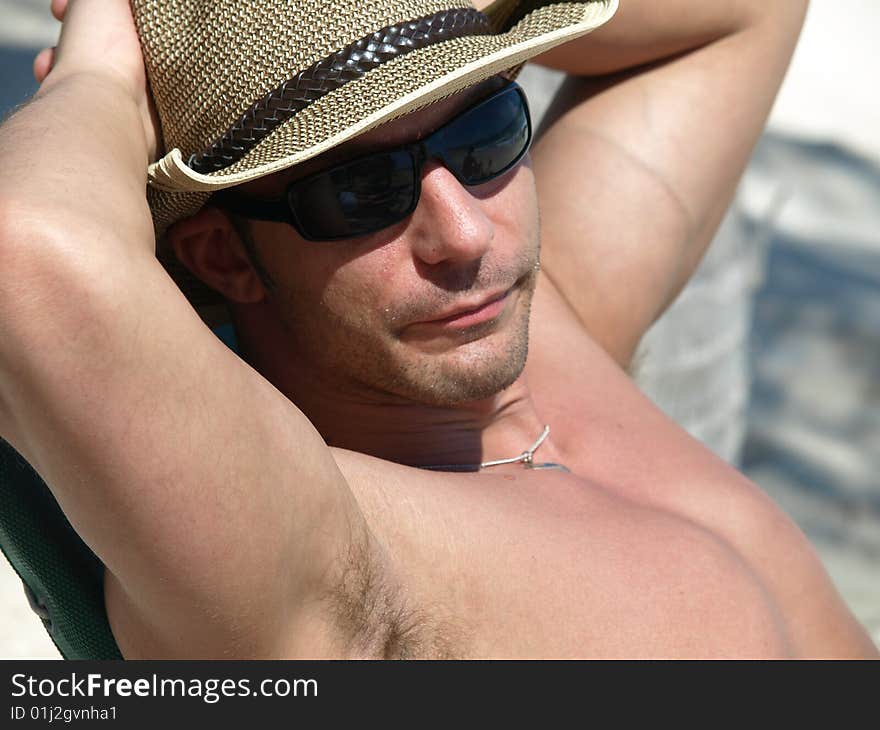 Handsome young man enjoying the sun shine sitting on the beach in Mexico. Handsome young man enjoying the sun shine sitting on the beach in Mexico.