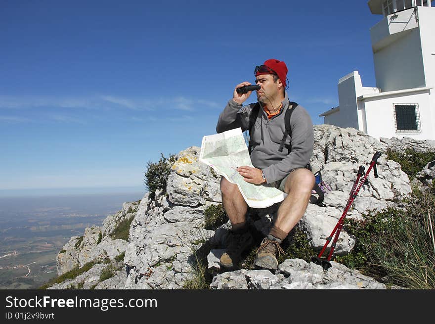 A handsome middle age hispanic latin man in a top of a in mountain hiking with a backpack looking the field with a googles. A handsome middle age hispanic latin man in a top of a in mountain hiking with a backpack looking the field with a googles