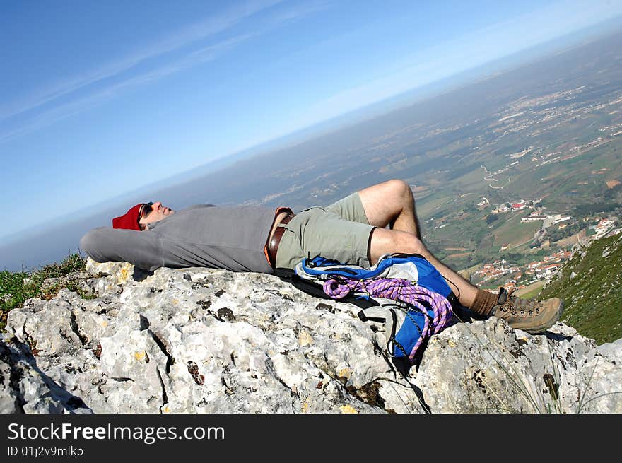 A handsome middle age hispanic latin man in a top of a in mountain hiking and resting with a beautiful landscape. A handsome middle age hispanic latin man in a top of a in mountain hiking and resting with a beautiful landscape