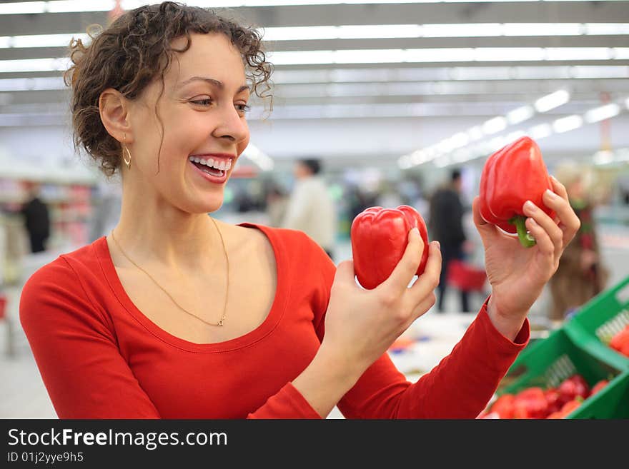 Young woman in shop with red sweet peppers