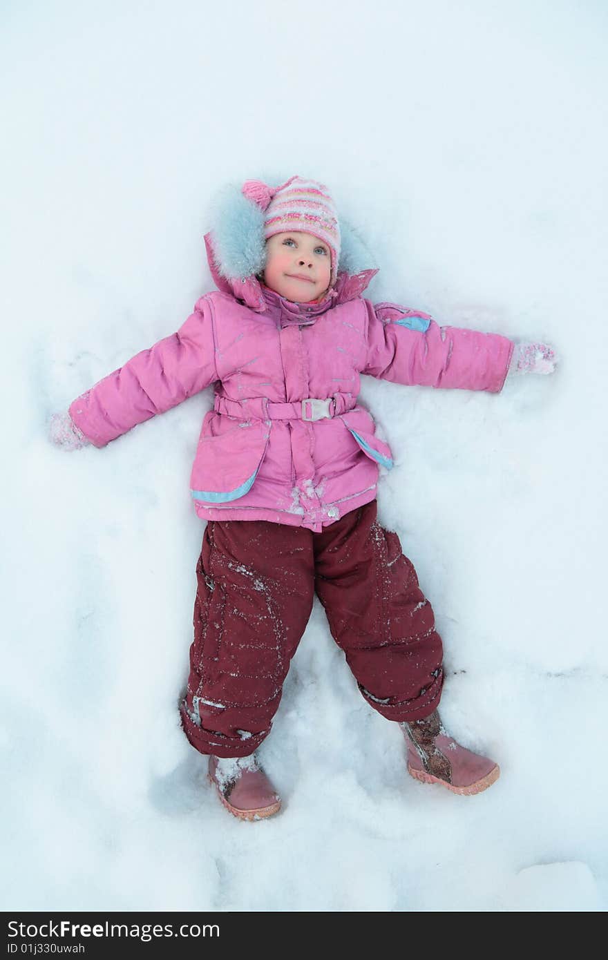 Little girl lying on snow, winter