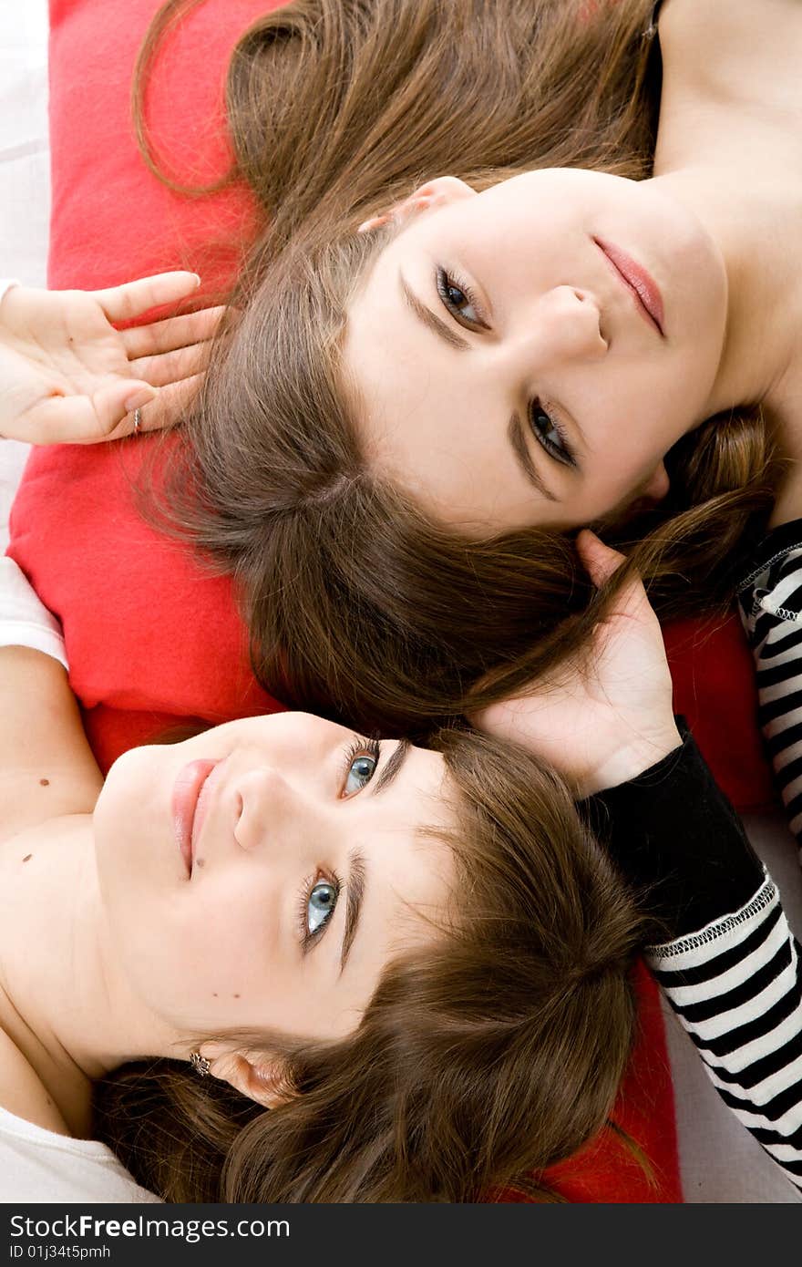 Two beautiful girls lying on red pillows. Two beautiful girls lying on red pillows