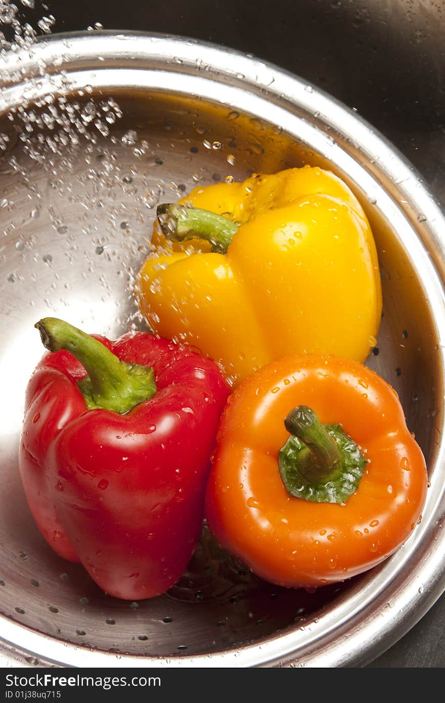 Yellow, red, and orange bell peppers washed in stainless steel metal collinder. Yellow, red, and orange bell peppers washed in stainless steel metal collinder