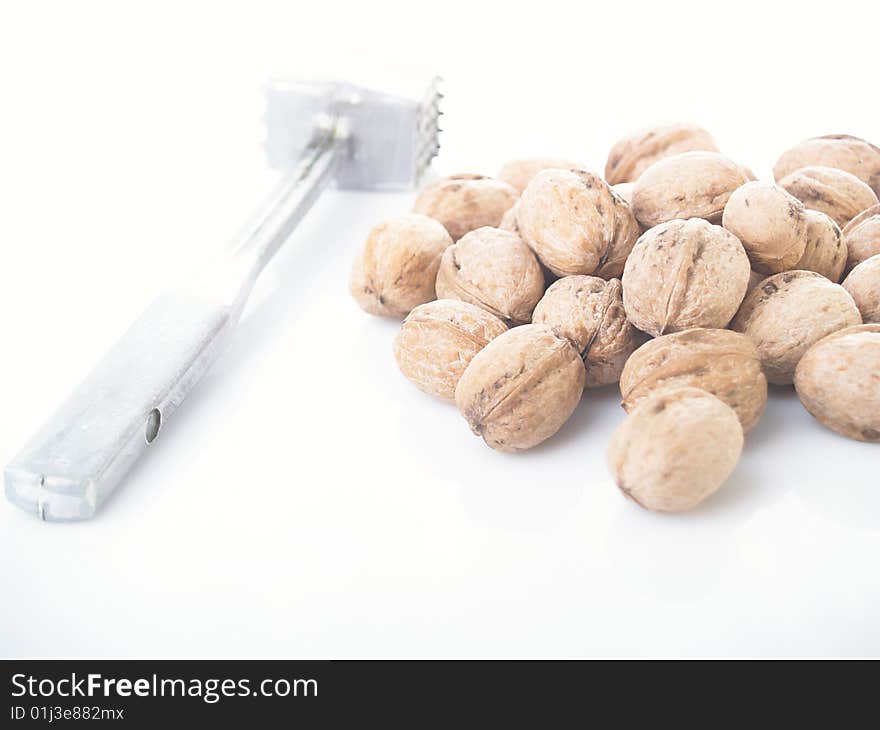 Walnuts and hammer on a white background