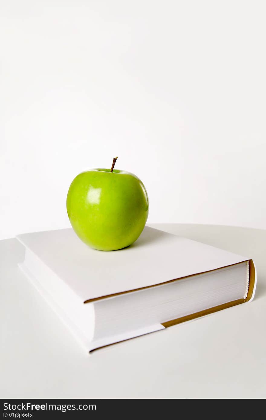 Still-life a green apple on the book, isolated