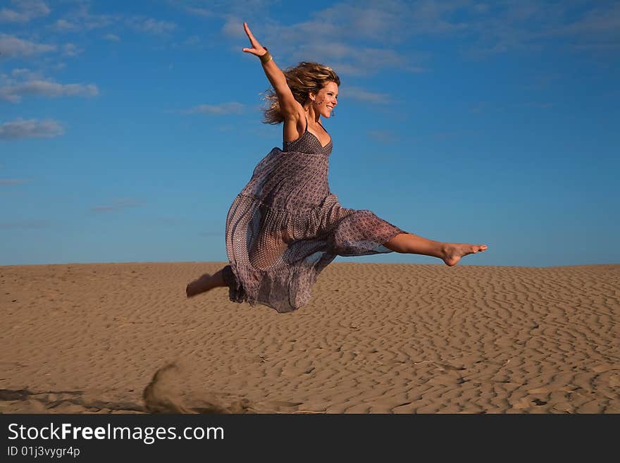 Young happy woman jumping in the sand