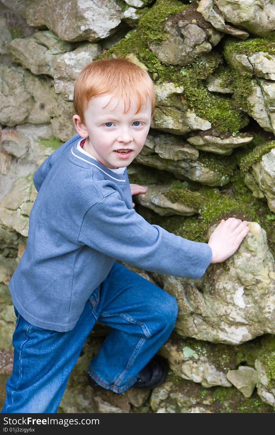 Young boy starting to climb up an old brick work wall. Young boy starting to climb up an old brick work wall