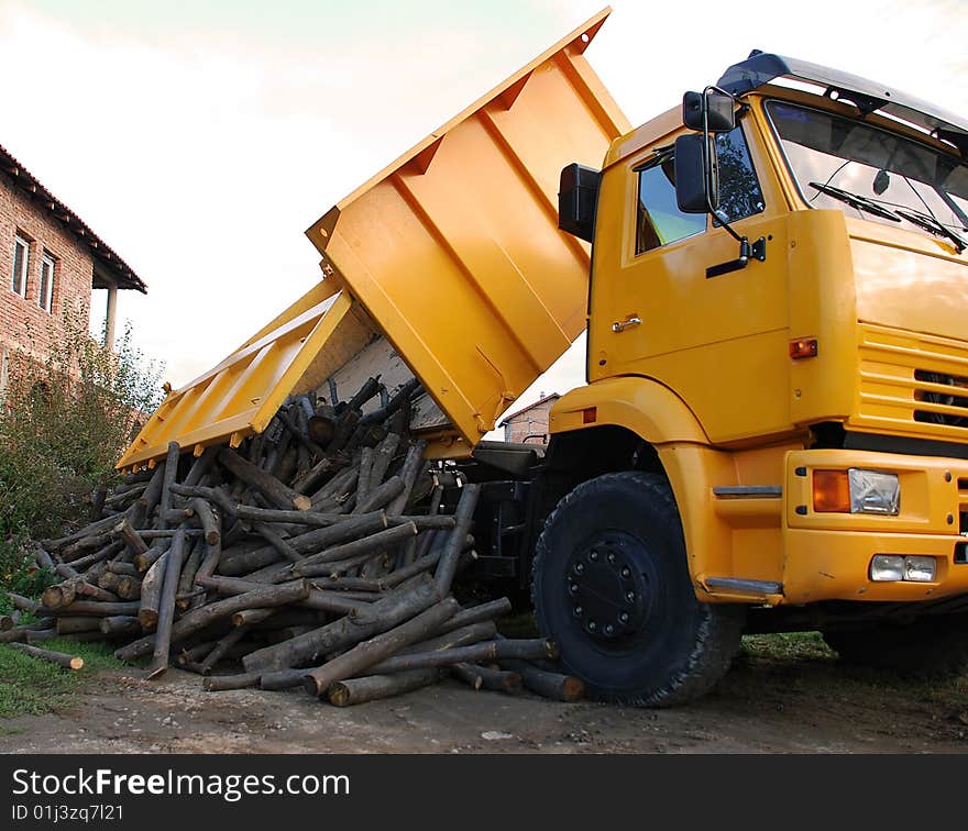 Unloading wood delivery from yellow truck outdoor