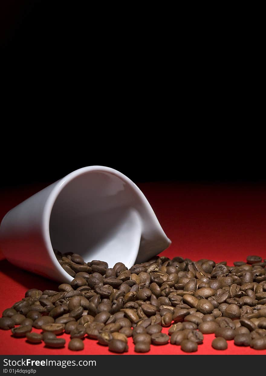 A fallen cup with coffee beans spread out.