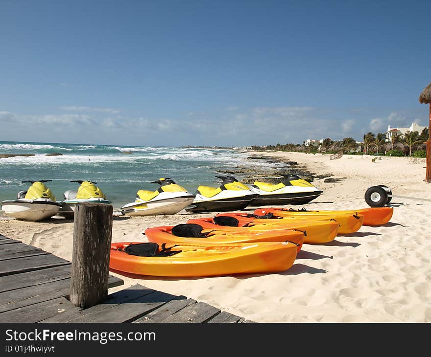 Kayaks and seadoos waiting for action on the beach of a mexican resort. Kayaks and seadoos waiting for action on the beach of a mexican resort.