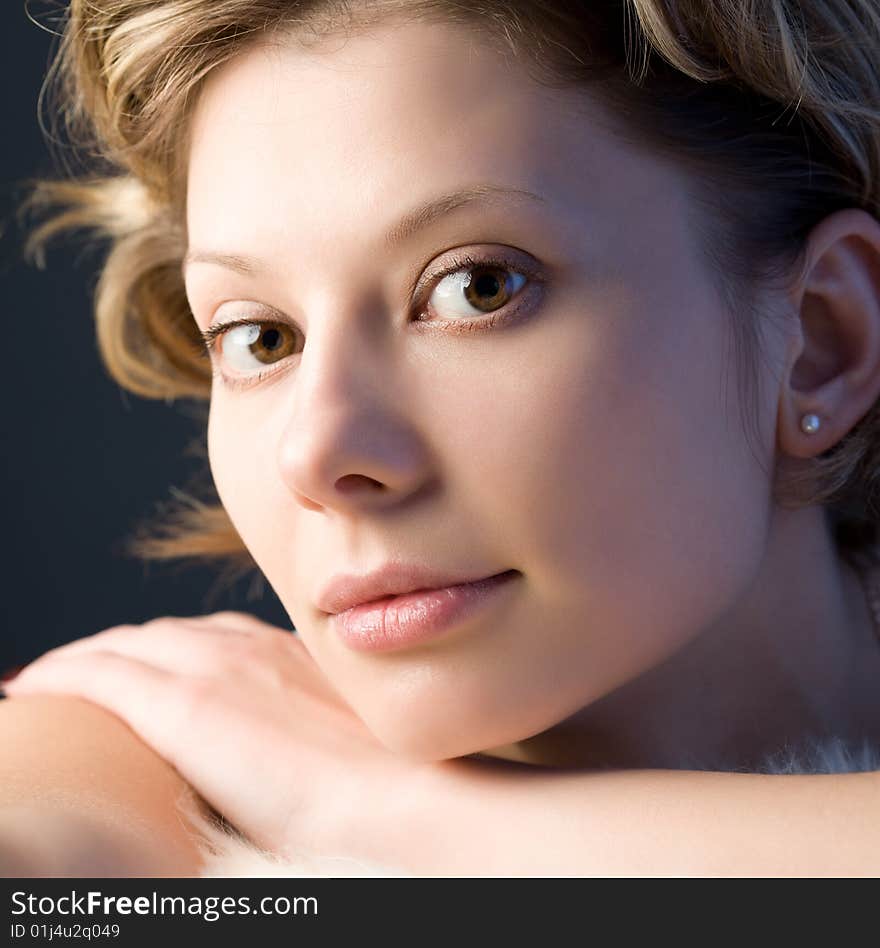 Portrait of pretty blond girl with white fur over black