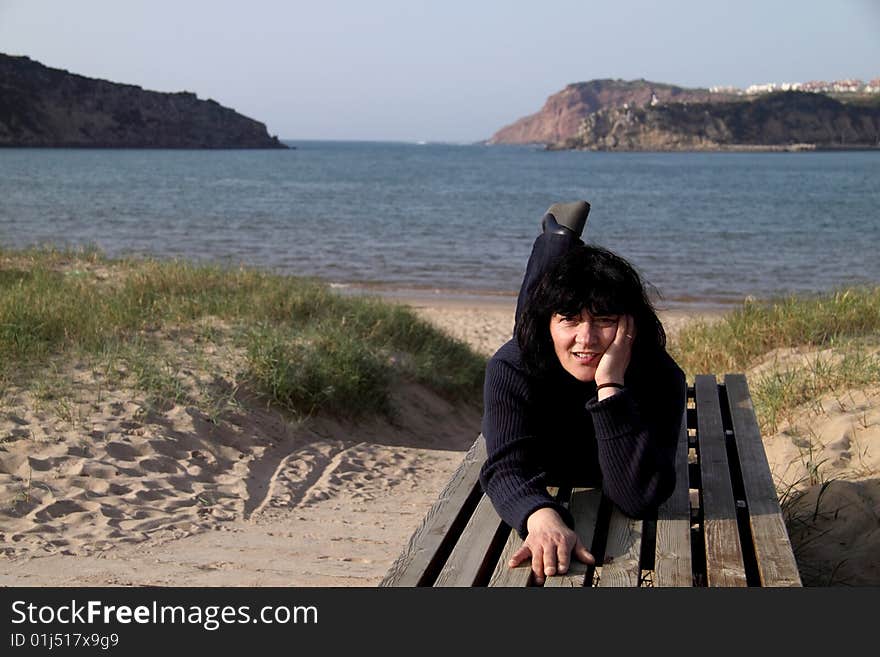 Resting on top of a large bank after a walk, happy woman, landscape the beach. Resting on top of a large bank after a walk, happy woman, landscape the beach.