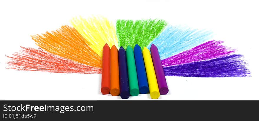 Seven wax crayons on a background the drawn semicircle from missing beams of colors of a rainbow