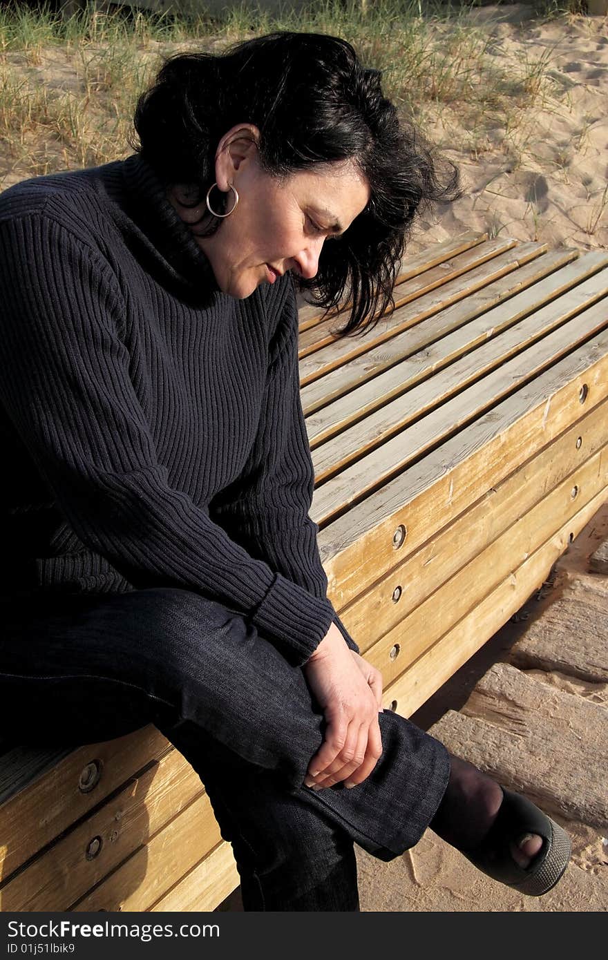 Sitting on the bench resting a foot, looking at the woman standing. Sitting on the bench resting a foot, looking at the woman standing