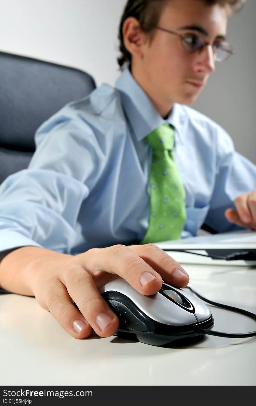 Young businessman at desk handling mouse, focus on mouse. Young businessman at desk handling mouse, focus on mouse