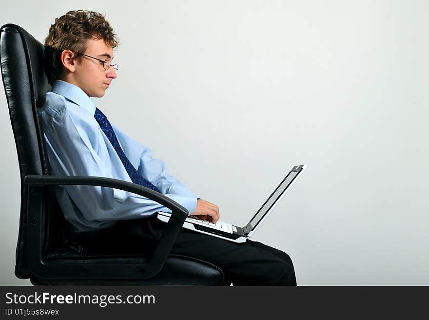 Young businessman sitting on office chair and using laptop. Young businessman sitting on office chair and using laptop