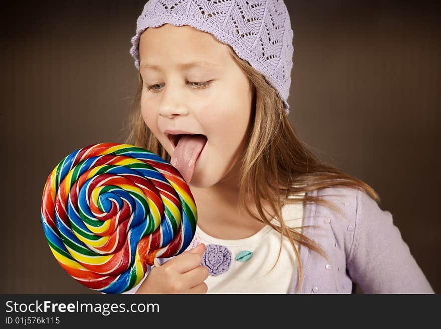 Cute young girl with lollipop and knit cap