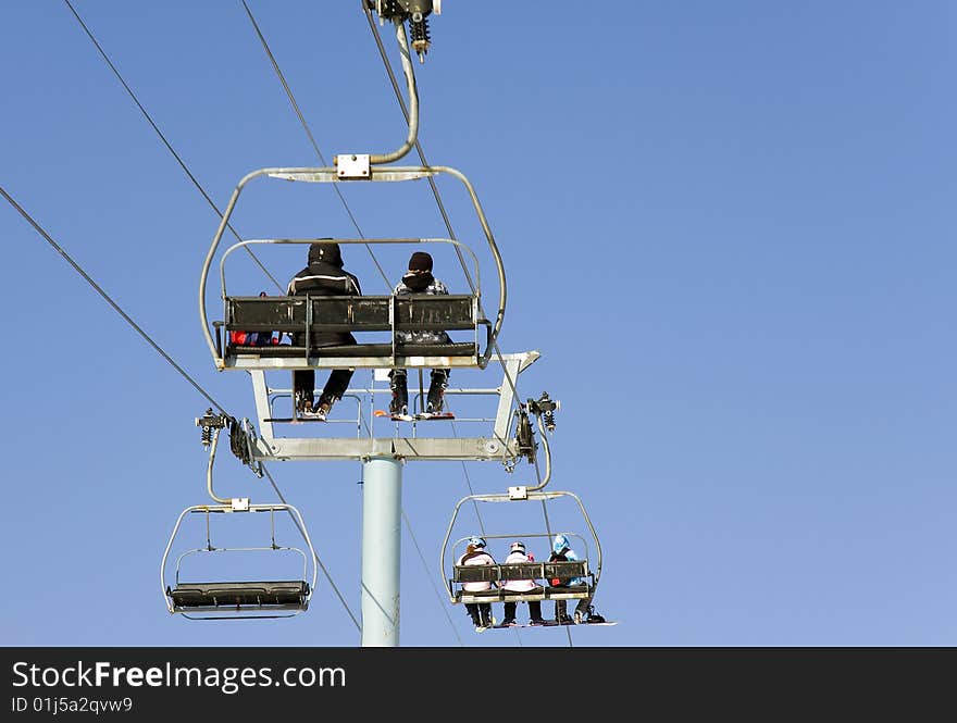 People going to ski in a chair lift. People going to ski in a chair lift.