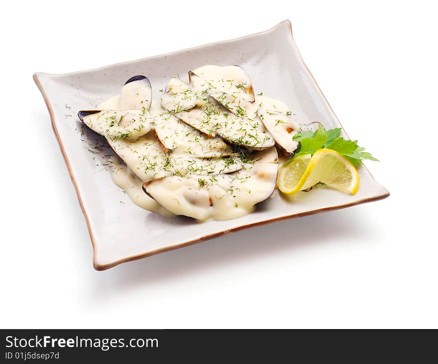 Mussel in white sauce with lemon slice and parsley strewed with dill on the squared plate over white background