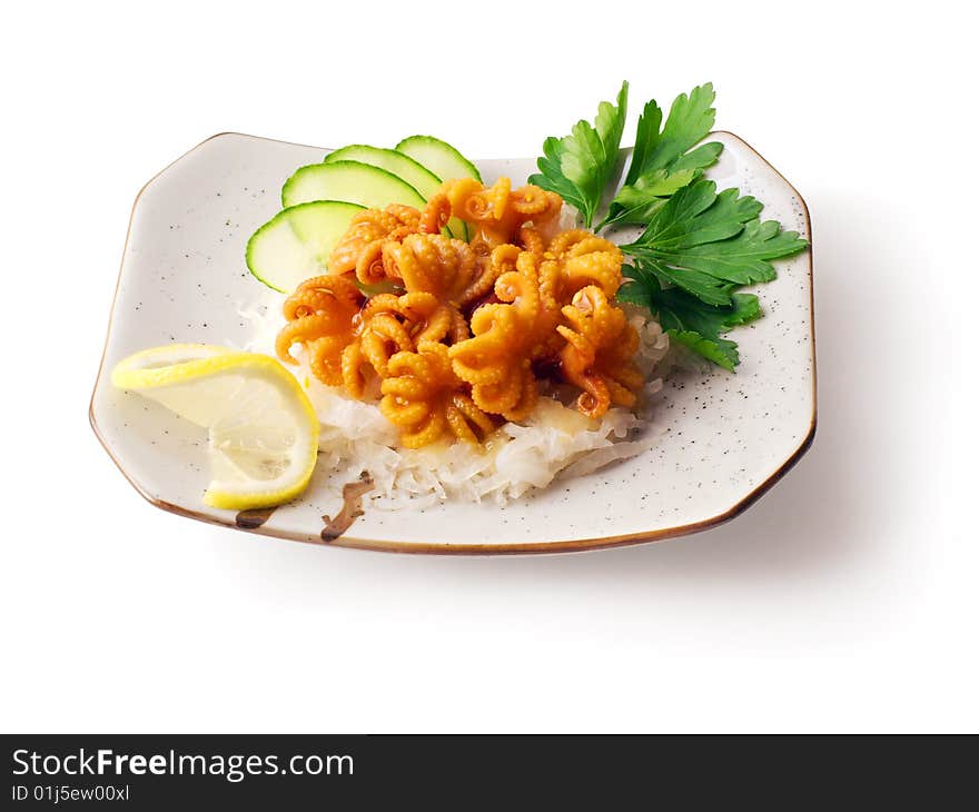 Mix from octopus, onion, cucumber with parsley and lemon on the squared plate over white background. Mix from octopus, onion, cucumber with parsley and lemon on the squared plate over white background