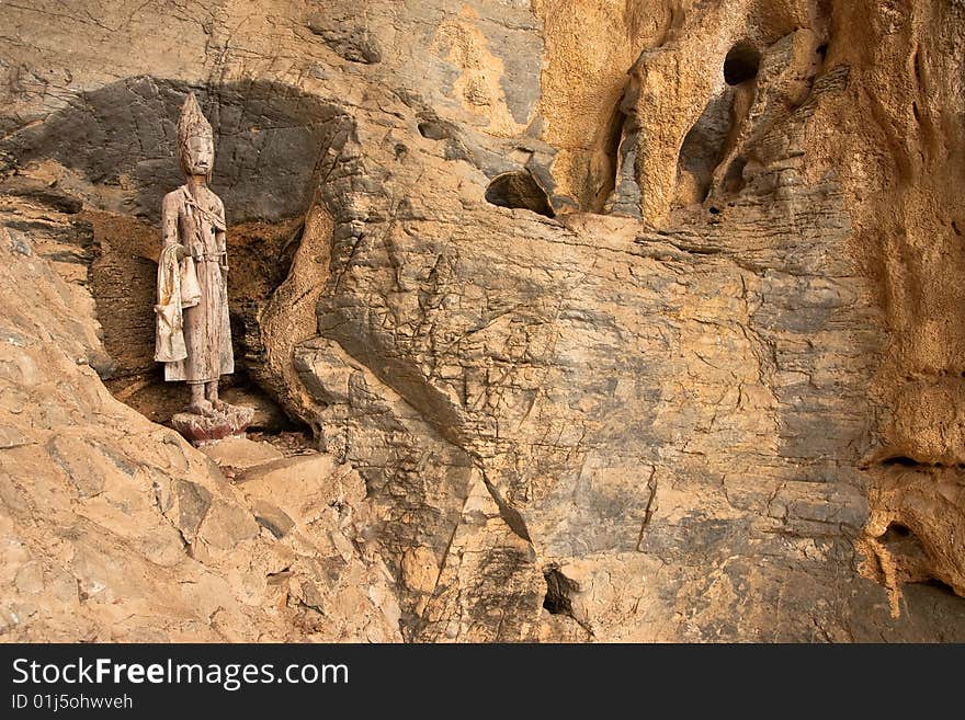 Broken wood Buddha image in cave.