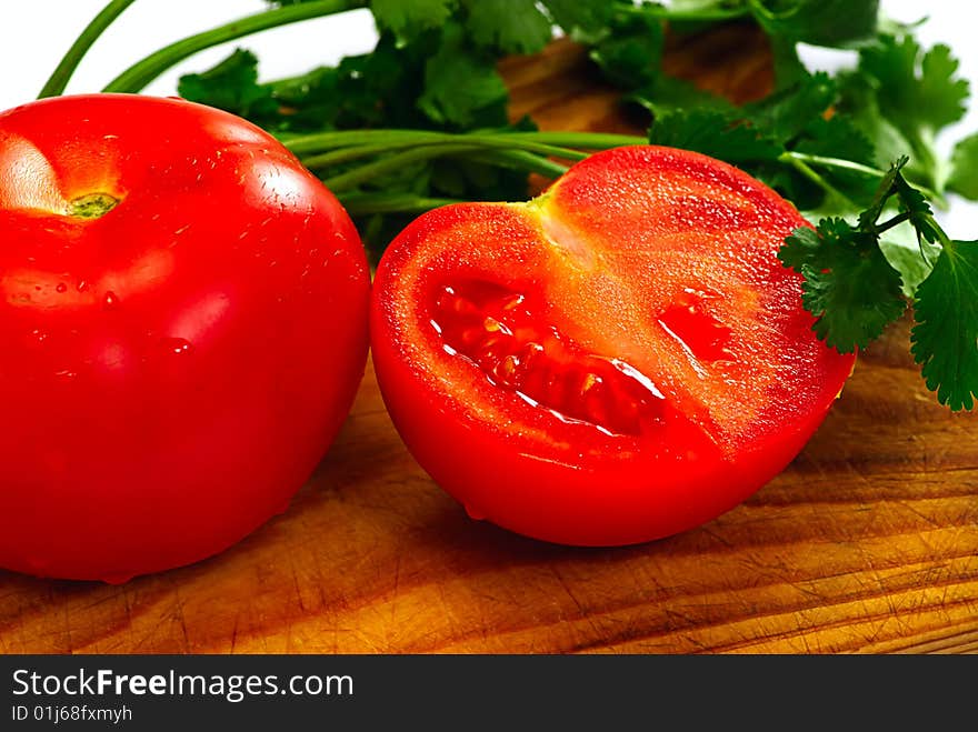 Tomato and coriander on a wooden plate