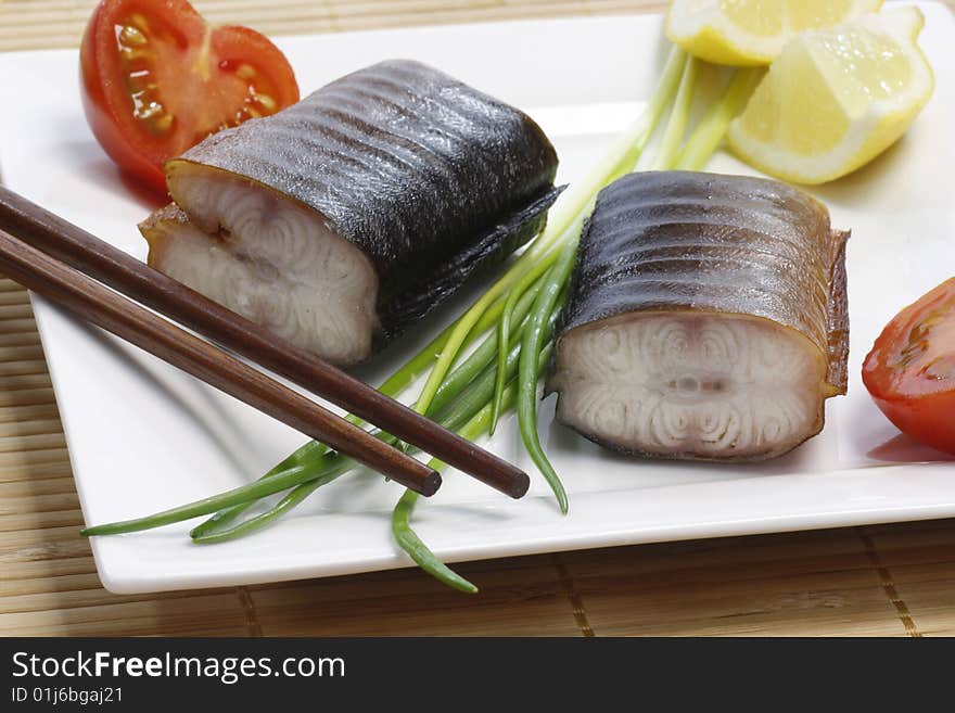 Pieces of smoked eel on a plate with garnish. Pieces of smoked eel on a plate with garnish