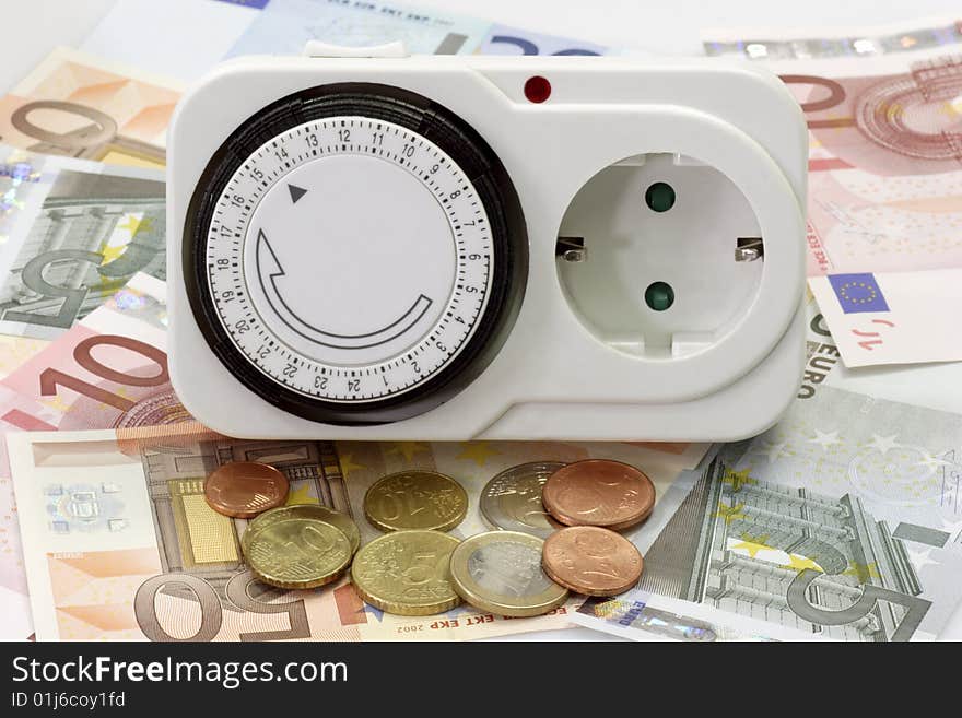 24 hours mechanical timer with Euro coins and bills over white background