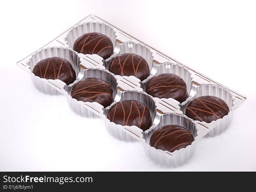 Small chocolate cakes covered with a layer of black chocolate and decorated with a pattern from a milk chocolate.