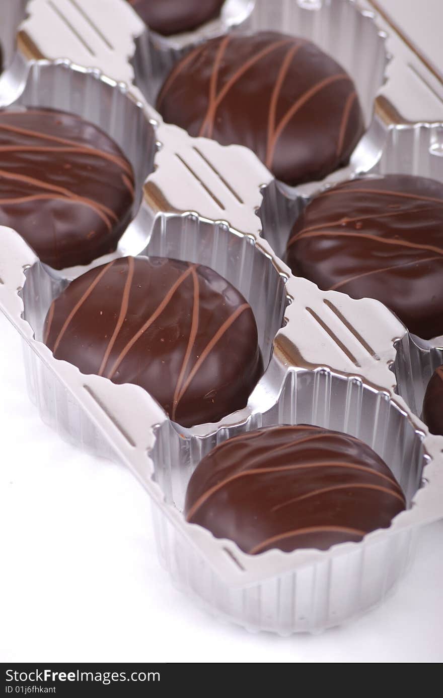 Small chocolate cakes covered with a layer of black chocolate and decorated with a pattern from a milk chocolate.