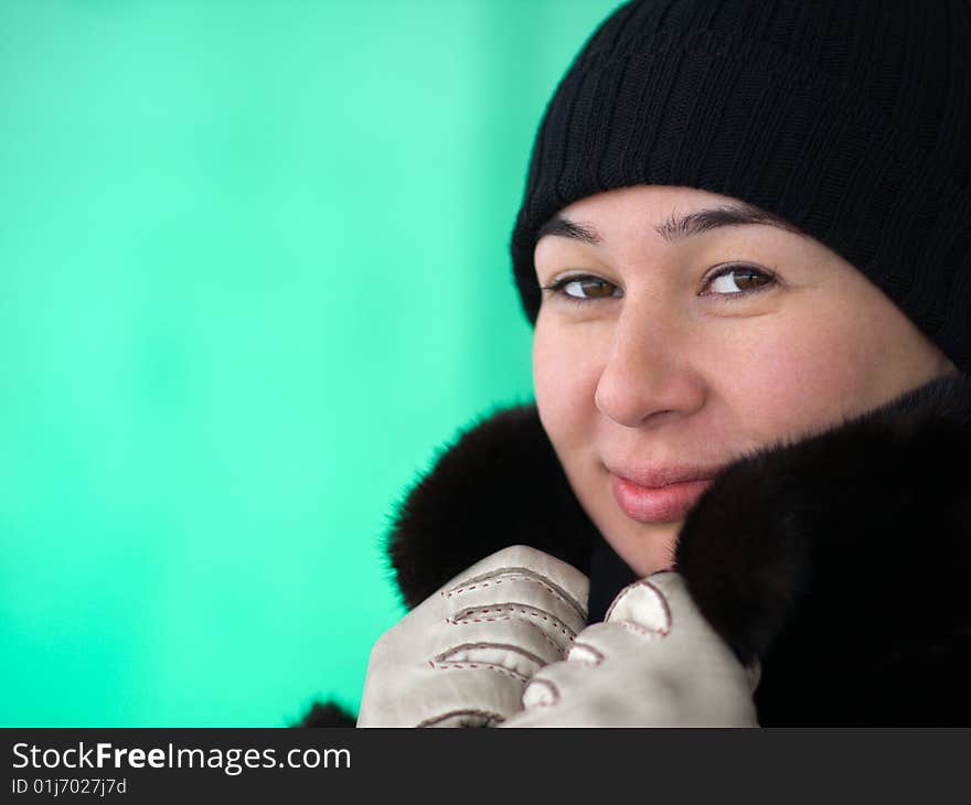 Pretty lady adjusting her fur coat' collar - portrait on green background