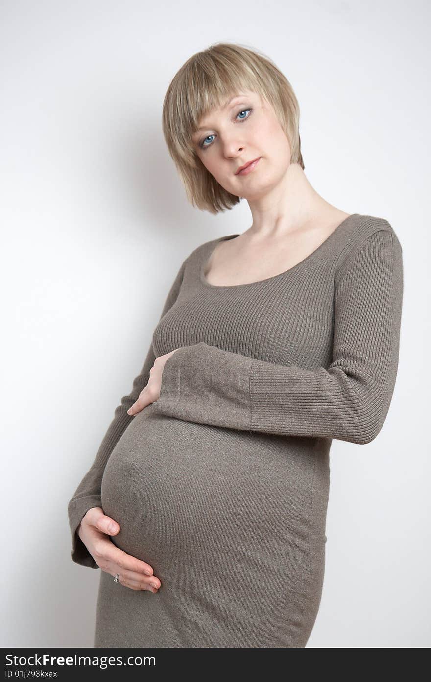 Full-body portrait of a pregnant woman in a dark beige dress