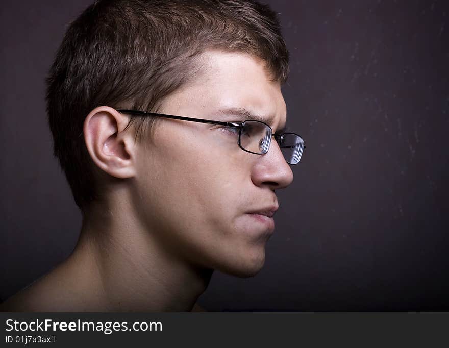 Man in glasses against a dark background.